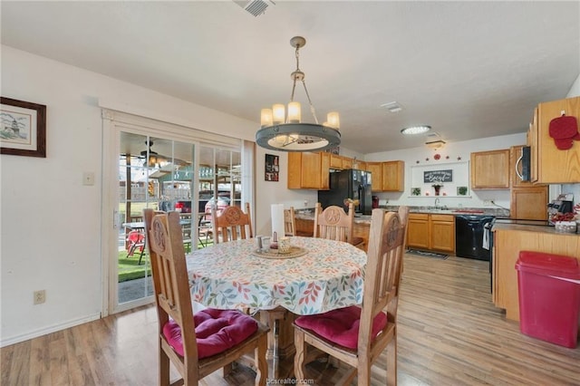 dining space with sink, a chandelier, and light hardwood / wood-style flooring