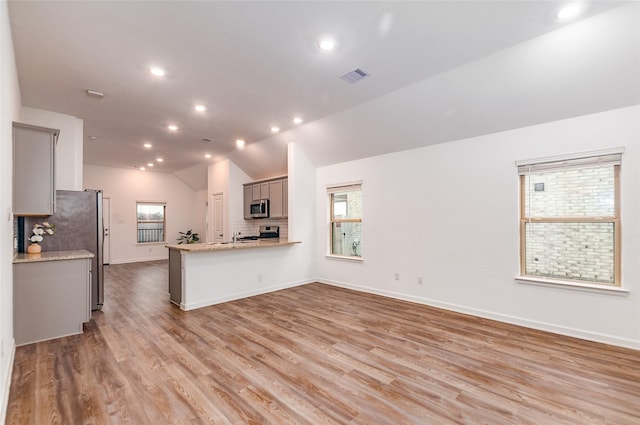 kitchen with light wood-type flooring, kitchen peninsula, gray cabinetry, and stainless steel appliances