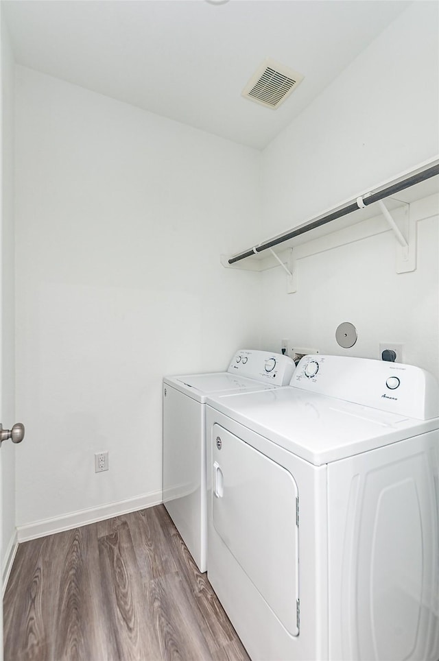 laundry area featuring washing machine and clothes dryer and hardwood / wood-style floors