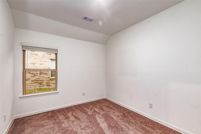 carpeted empty room featuring vaulted ceiling