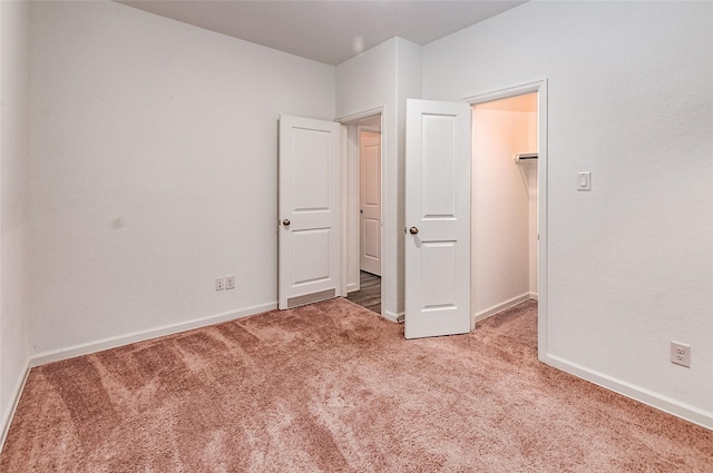 unfurnished bedroom with carpet floors, a closet, and a spacious closet