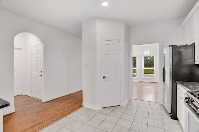 kitchen with white cabinets, appliances with stainless steel finishes, dark stone countertops, and light tile patterned floors