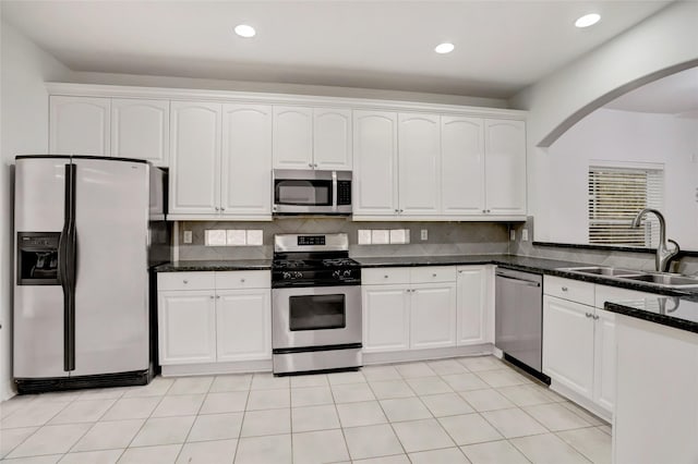 kitchen with white cabinets, dark stone counters, sink, and stainless steel appliances