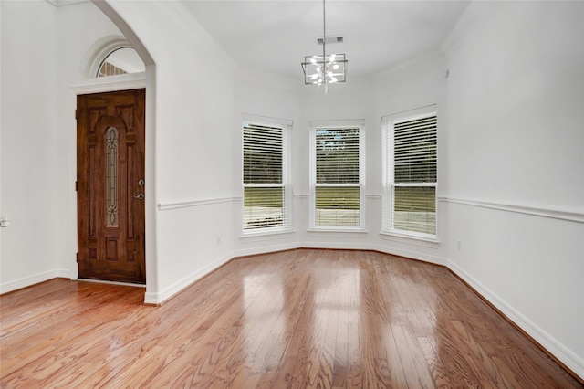 entrance foyer featuring a wealth of natural light, an inviting chandelier, and ornamental molding