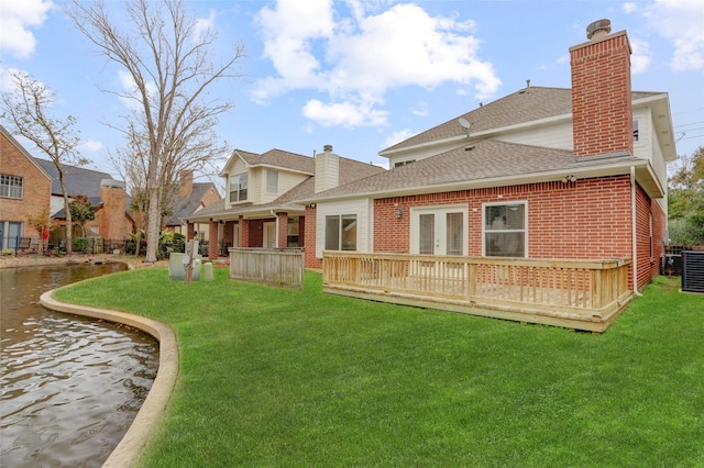 rear view of property featuring a wooden deck and a lawn