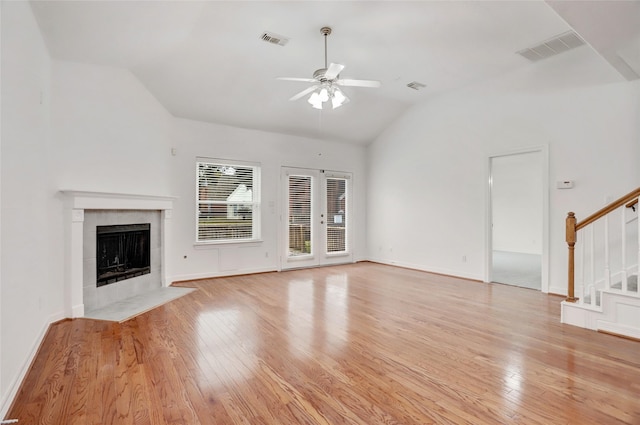 unfurnished living room featuring vaulted ceiling, ceiling fan, a fireplace, and light wood-type flooring