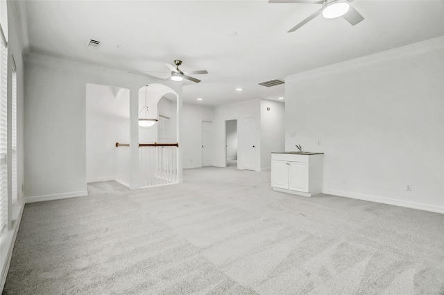 carpeted empty room with ceiling fan, ornamental molding, and sink