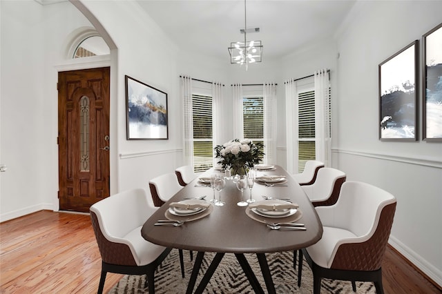 dining space with light wood-type flooring, crown molding, and a chandelier