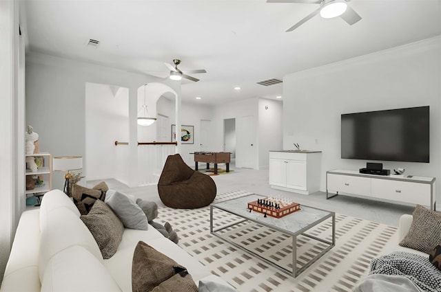 carpeted living room featuring ceiling fan and crown molding