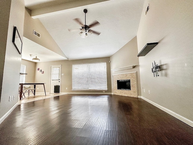 unfurnished living room featuring ceiling fan, a textured ceiling, hardwood / wood-style floors, and vaulted ceiling with beams