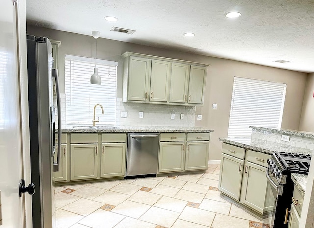 kitchen with pendant lighting, decorative backsplash, sink, stainless steel appliances, and light stone counters