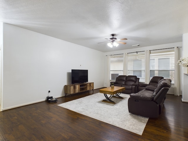 living room featuring ceiling fan, a textured ceiling, and dark hardwood / wood-style floors