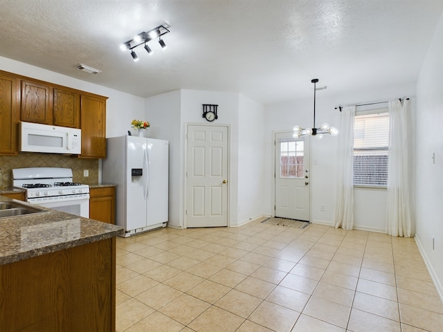 kitchen featuring white appliances, an inviting chandelier, backsplash, hanging light fixtures, and light tile patterned flooring