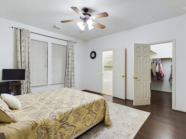 bedroom with a spacious closet, connected bathroom, dark hardwood / wood-style flooring, a closet, and ceiling fan