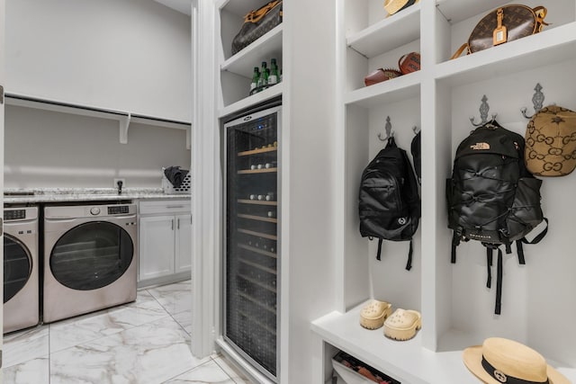 clothes washing area featuring washing machine and dryer, cabinets, and beverage cooler