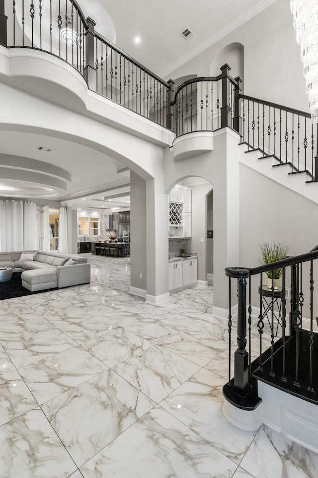 foyer entrance featuring a towering ceiling and ornamental molding