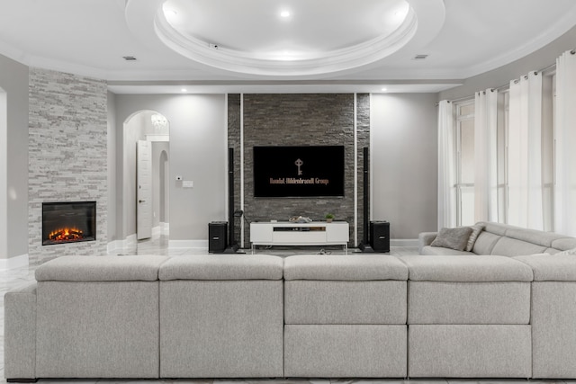 living room featuring a raised ceiling and a stone fireplace