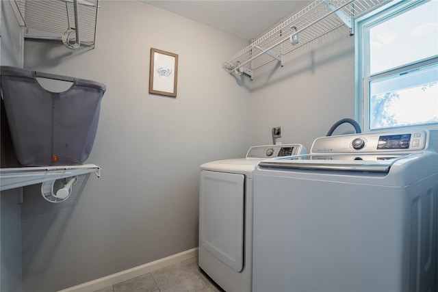 clothes washing area featuring laundry area, light tile patterned flooring, baseboards, and separate washer and dryer