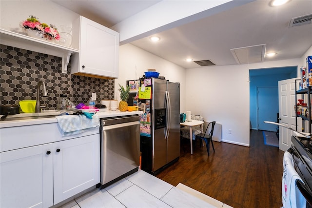 kitchen featuring stainless steel appliances, visible vents, white cabinets, light countertops, and backsplash