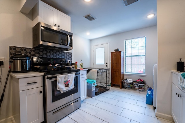 kitchen with tasteful backsplash, visible vents, appliances with stainless steel finishes, and white cabinets