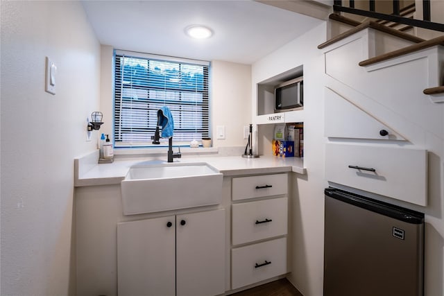 kitchen with white cabinets, light countertops, and a sink