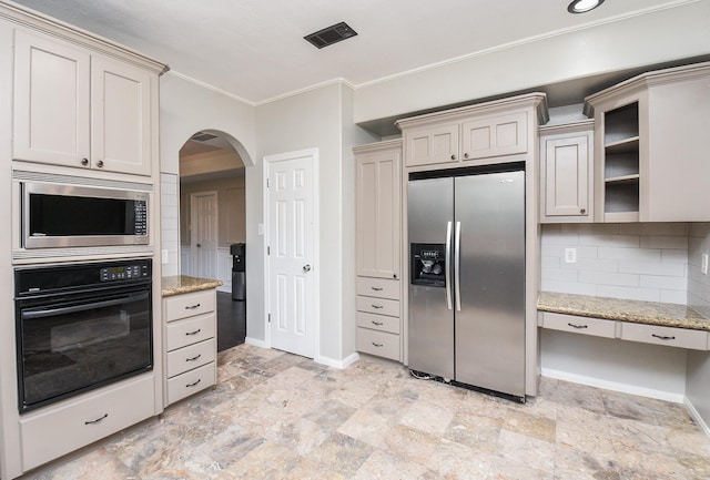 kitchen featuring backsplash, light stone countertops, stainless steel appliances, and cream cabinets