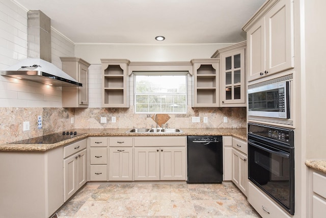 kitchen with black appliances, wall chimney exhaust hood, tasteful backsplash, sink, and light stone counters