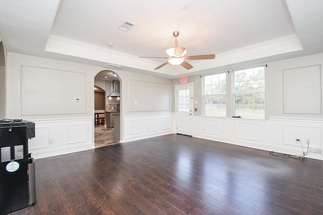 unfurnished room with ceiling fan, dark wood-type flooring, ornamental molding, and a raised ceiling