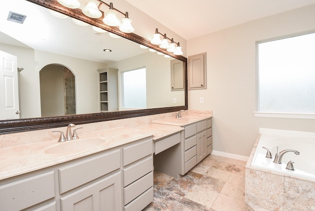 bathroom with tiled tub, vanity, and a healthy amount of sunlight