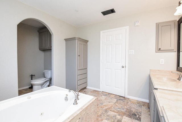 bathroom featuring a relaxing tiled tub, toilet, and vanity