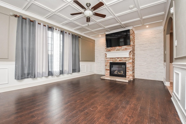 unfurnished living room featuring ceiling fan, hardwood / wood-style floors, a stone fireplace, and coffered ceiling