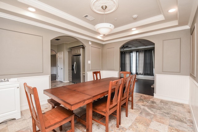 dining area with a raised ceiling and ornamental molding