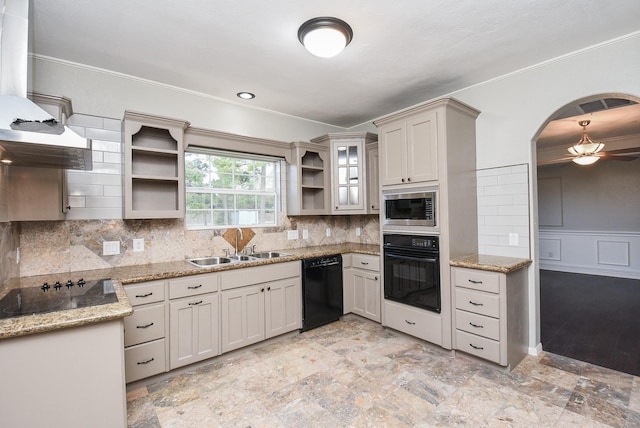 kitchen featuring light stone countertops, sink, black appliances, and tasteful backsplash