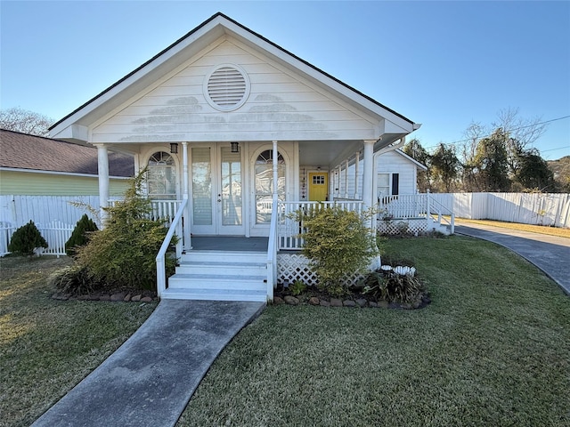 bungalow with covered porch, a front yard, and french doors