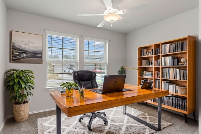 carpeted home office featuring ceiling fan