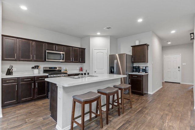 kitchen featuring sink, appliances with stainless steel finishes, dark hardwood / wood-style flooring, and a kitchen island with sink