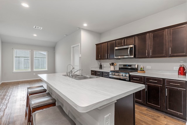 kitchen featuring light hardwood / wood-style floors, sink, dark brown cabinetry, an island with sink, and stainless steel appliances