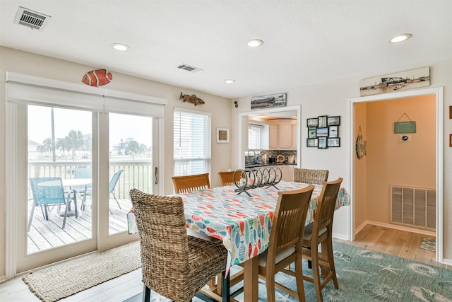 dining area featuring light hardwood / wood-style floors and a water view