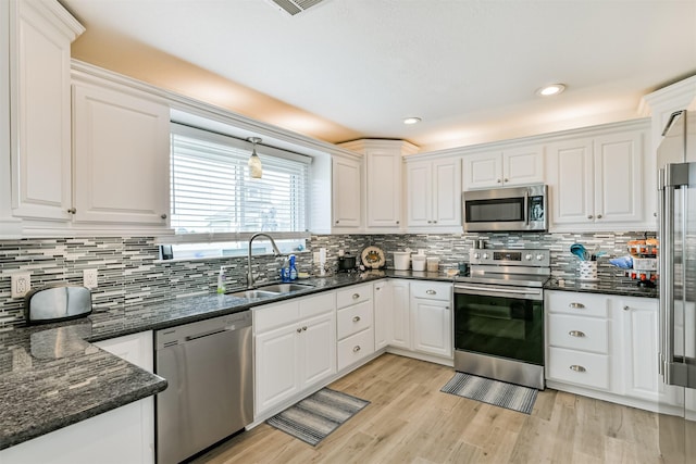 kitchen featuring dark stone countertops, sink, hanging light fixtures, appliances with stainless steel finishes, and white cabinets