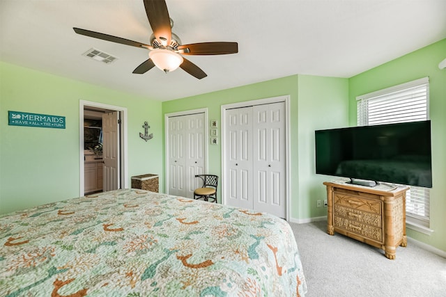 carpeted bedroom featuring ceiling fan and two closets