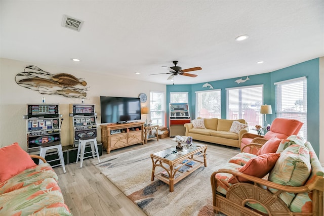 living room with ceiling fan, plenty of natural light, and light hardwood / wood-style flooring