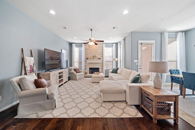 living room with ceiling fan, a wealth of natural light, light hardwood / wood-style flooring, and a fireplace