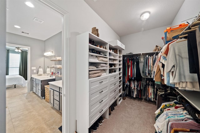 spacious closet with light carpet and ceiling fan