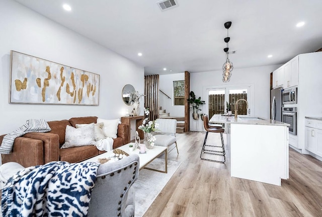 living room featuring sink and light hardwood / wood-style flooring