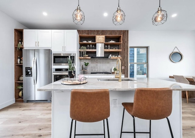 kitchen featuring pendant lighting, stainless steel appliances, sink, a kitchen island with sink, and light stone counters