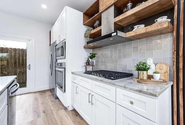 kitchen with ventilation hood, appliances with stainless steel finishes, white cabinetry, and light stone counters