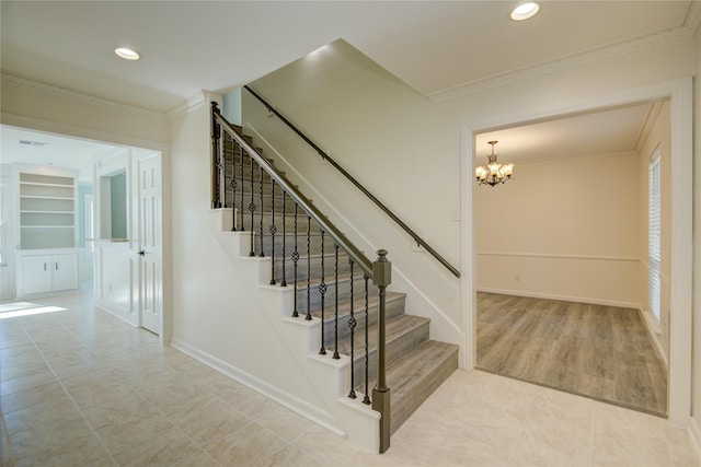 staircase featuring built in shelves, tile patterned floors, crown molding, and a chandelier