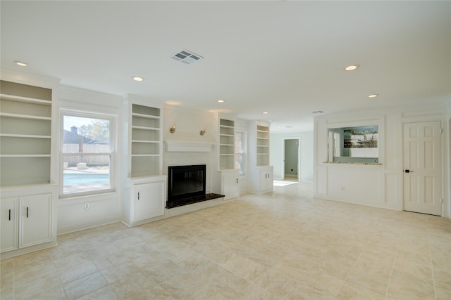 unfurnished living room with built in features, ornamental molding, and a fireplace