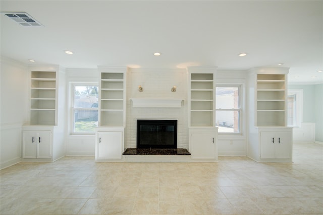 unfurnished living room with a brick fireplace, plenty of natural light, and ornamental molding