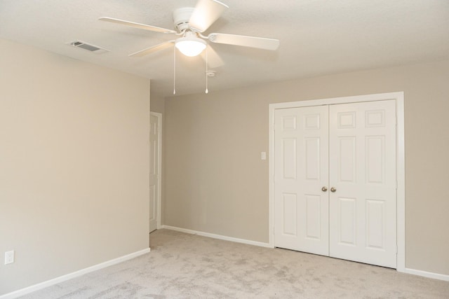 unfurnished bedroom featuring ceiling fan, light colored carpet, and a closet